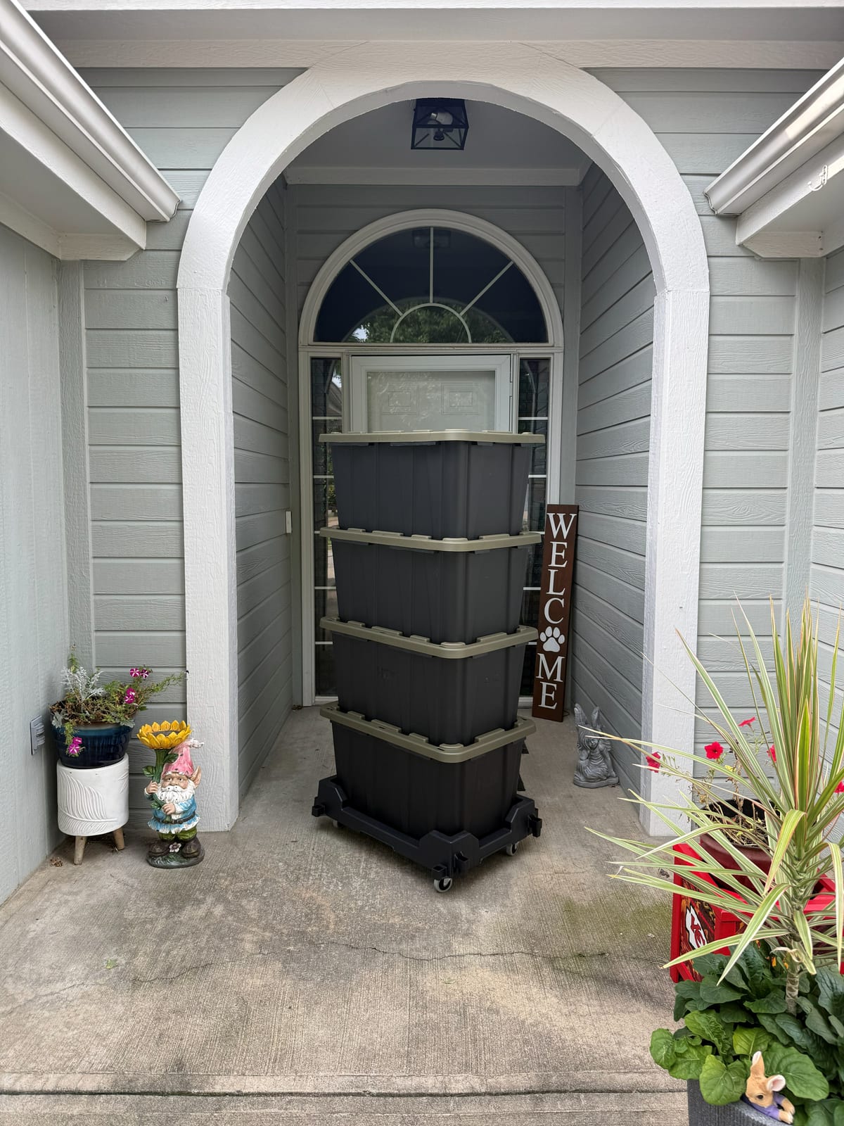 A stack of totes on a Tote Taxi delivered to a covered front porch