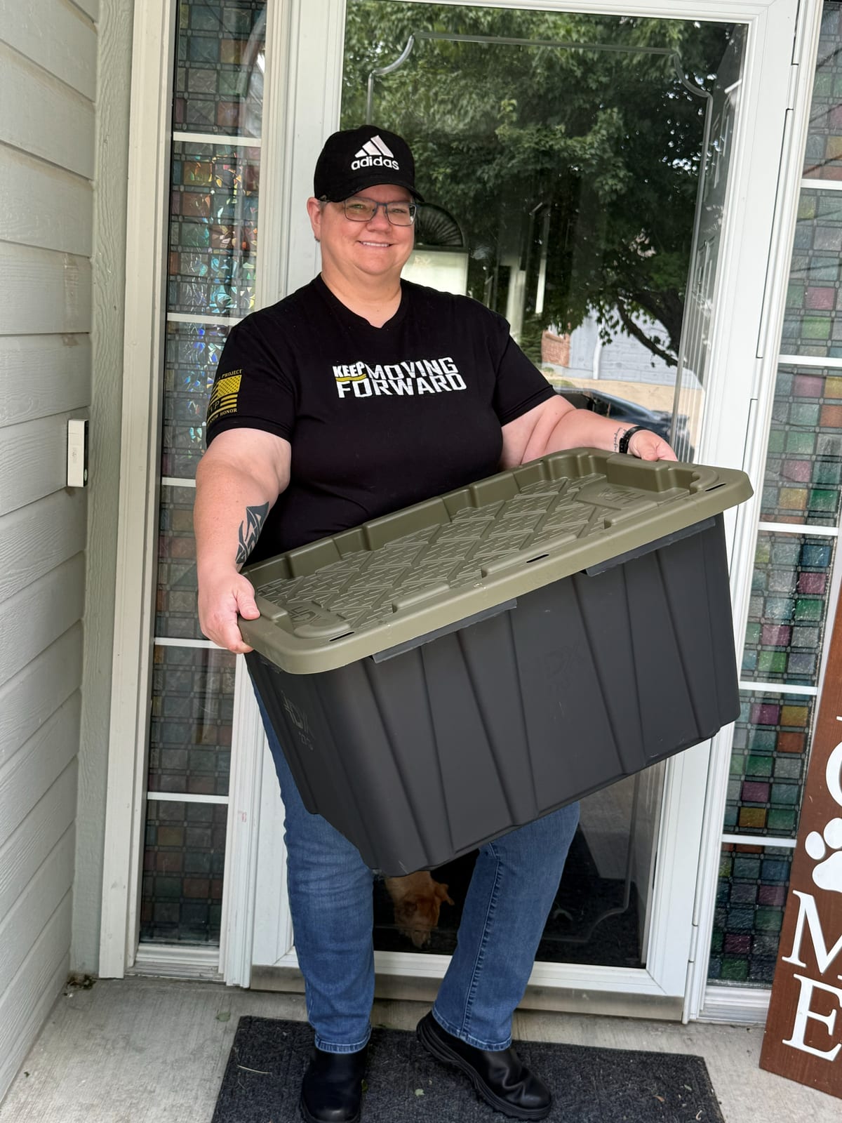 Shelley carrying a tote out a front door
